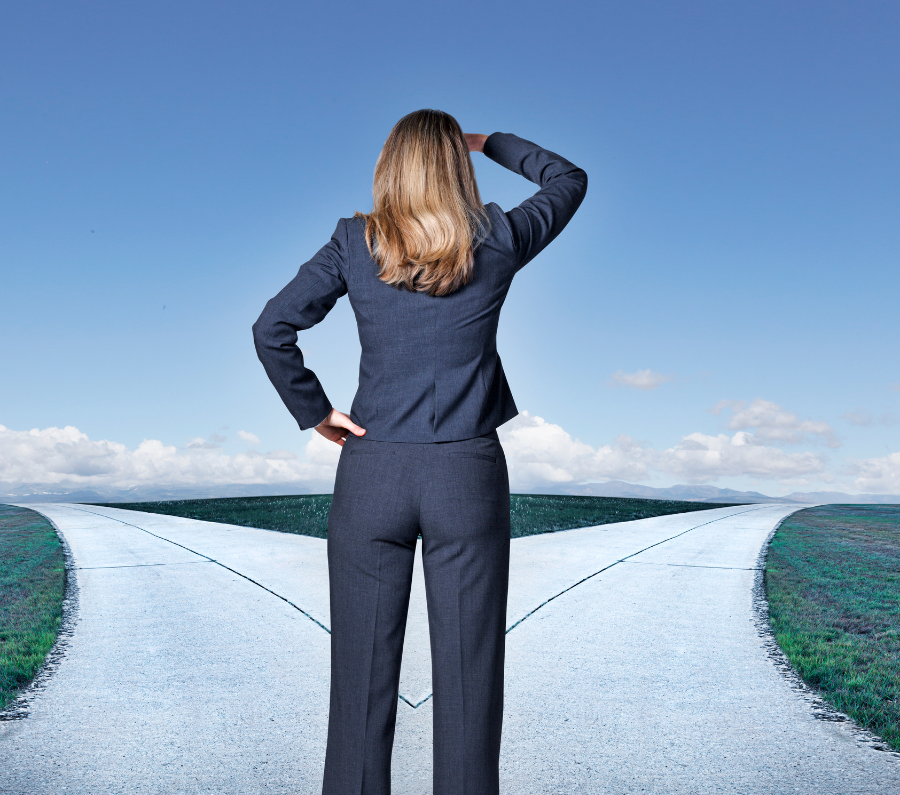 Businesswoman standing at a crossroads, contemplating which path to choose